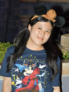 A woman smiles while wearing a cartoon Mickey Mouse shirt. 